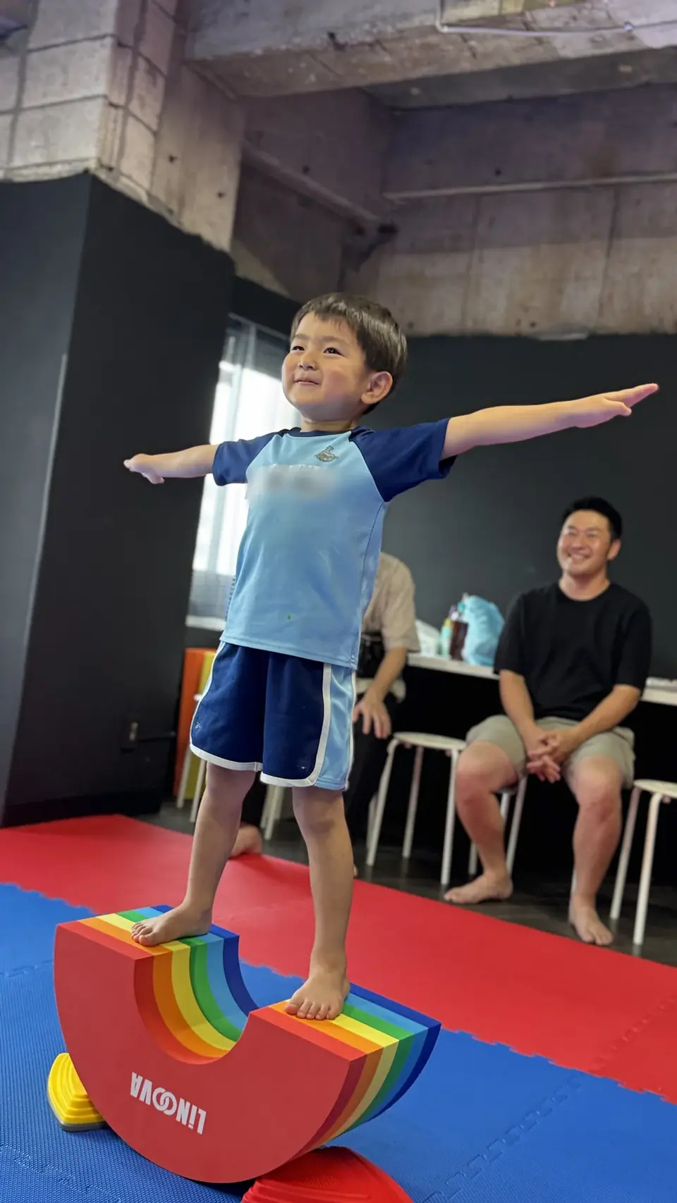 バランス遊具の上で両手を広げ、身体の感覚をたしかめる子ども