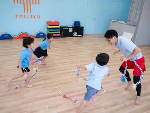 ひもを使った遊びで、トレーナーと子どもたちが走り回っている様子